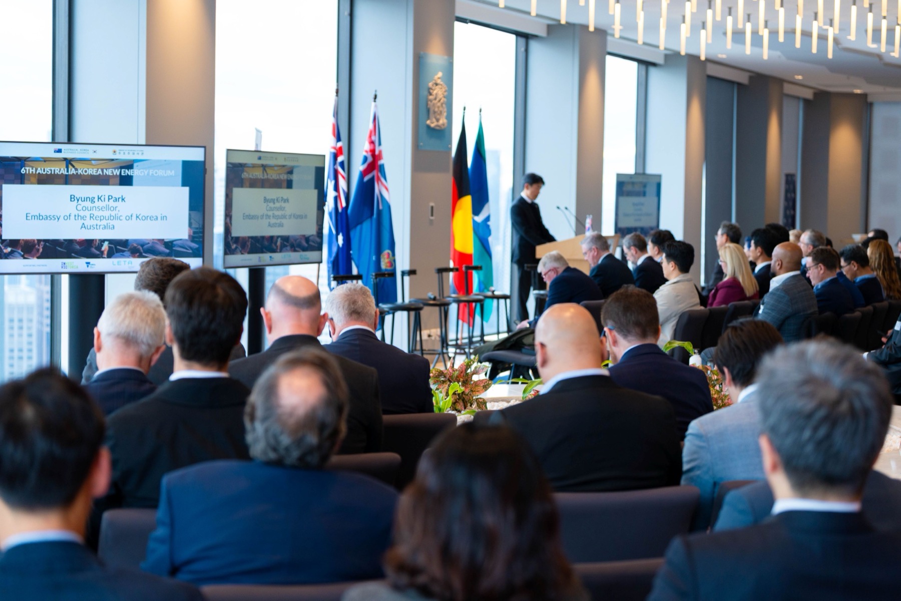 Delegates seated for the 6th Australia-Korea New Energy Forum, with a speaker from the Korean embassy introduced on screen