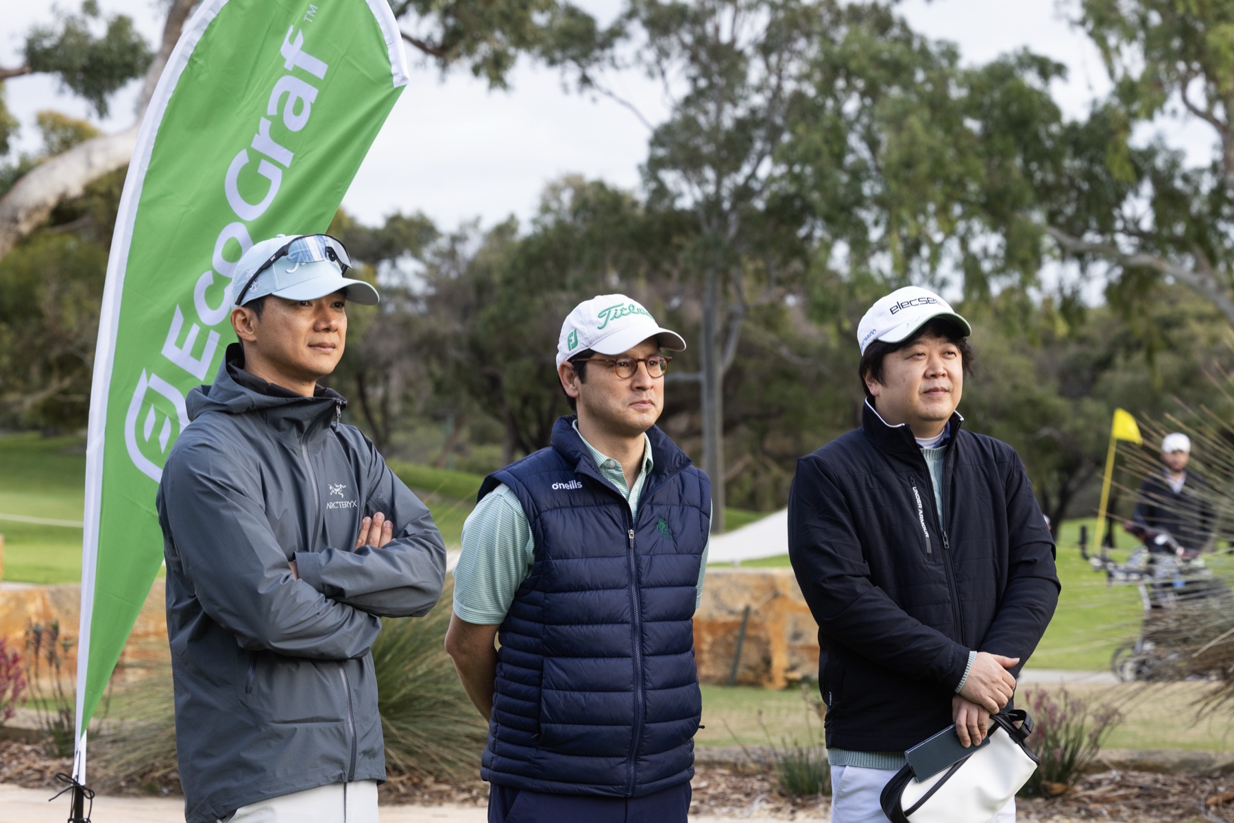 Three golfers beside an EcoGraf banner on the course