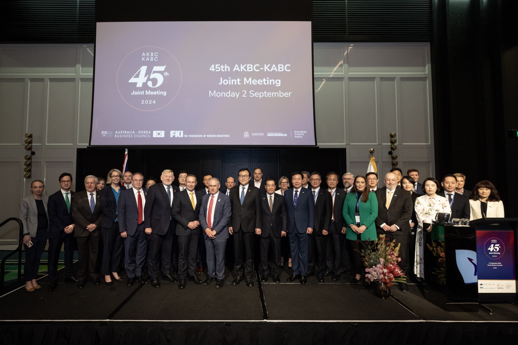 The Australian and Korean delegations posed on stage at the 45th AKBC-KABC Joint Meeting, Perth, under the event’s own signage