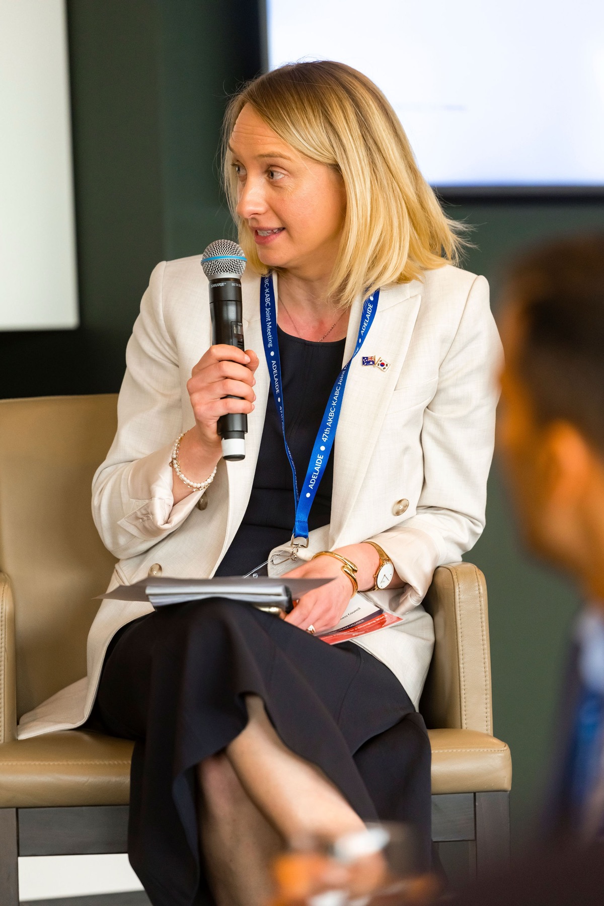 A panellist speaking into a microphone at the 47th AKBC-KABC Joint Meeting, wearing an Adelaide delegate lanyard